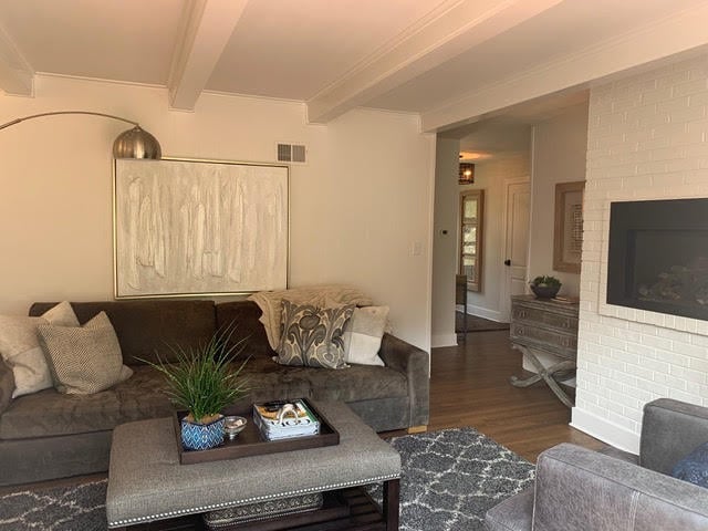 A cozy living room with a dark gray couch, decorative pillows, and a white brick fireplace, accented by soft lighting and modern decor | Dusty Rhodes.